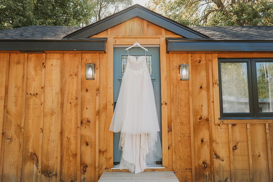A wedding dress hanging outside of a cabin