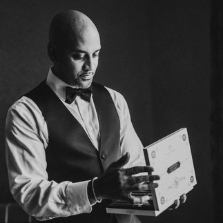 A groomsmen opening a box of cigars in black and white