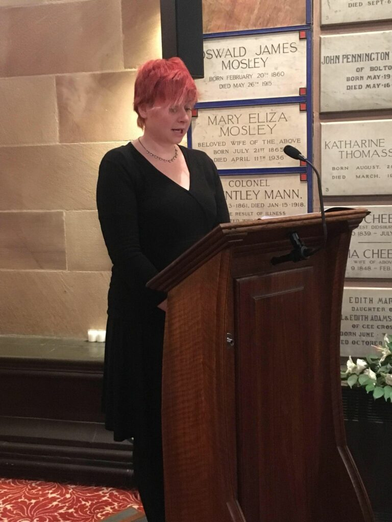Female funeral celebrant stood at lecturn in cremation chapel