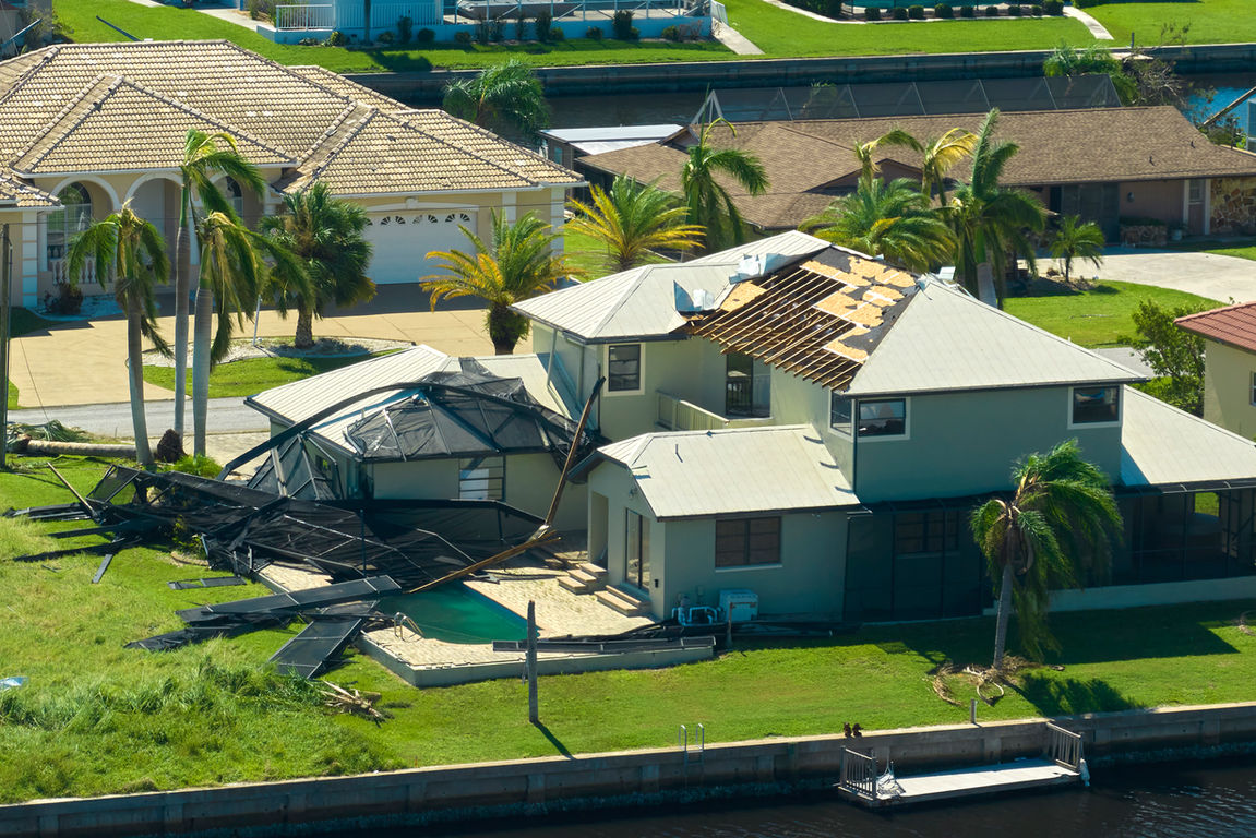 Home with roof damage and a pool enclosure destroyed by a storm