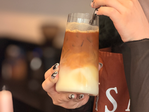 A customer drinking a layered iced coffee at RASA