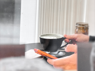 A customer holding a cup and saucer by the café window