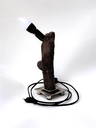 Candeeiro de design único com madeira flutuante (driftwood) carbonizada sobre base metálica quadrada.