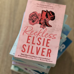 Cover of Reckless by Elsie Silver, displaying a rose and cowboy boots illustration on a muted red textured background.