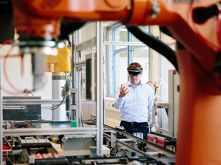 Engineer works with a HoloLens place a virtual robotic arm into the production line.