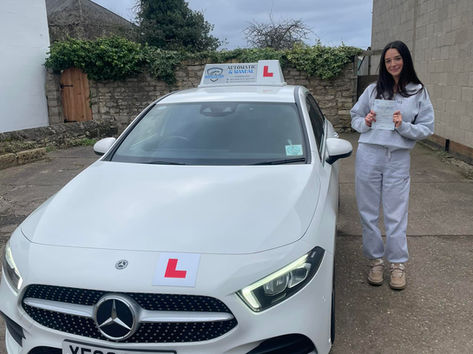 Successful learner driver standing outside with certificate