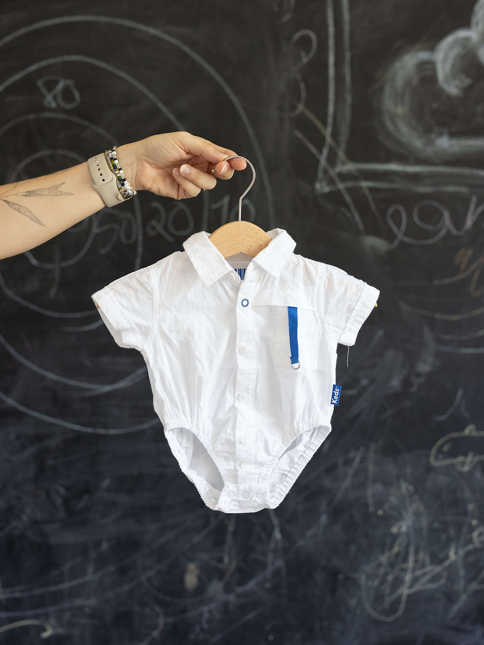 חולצת תינוק לבנה תלויה