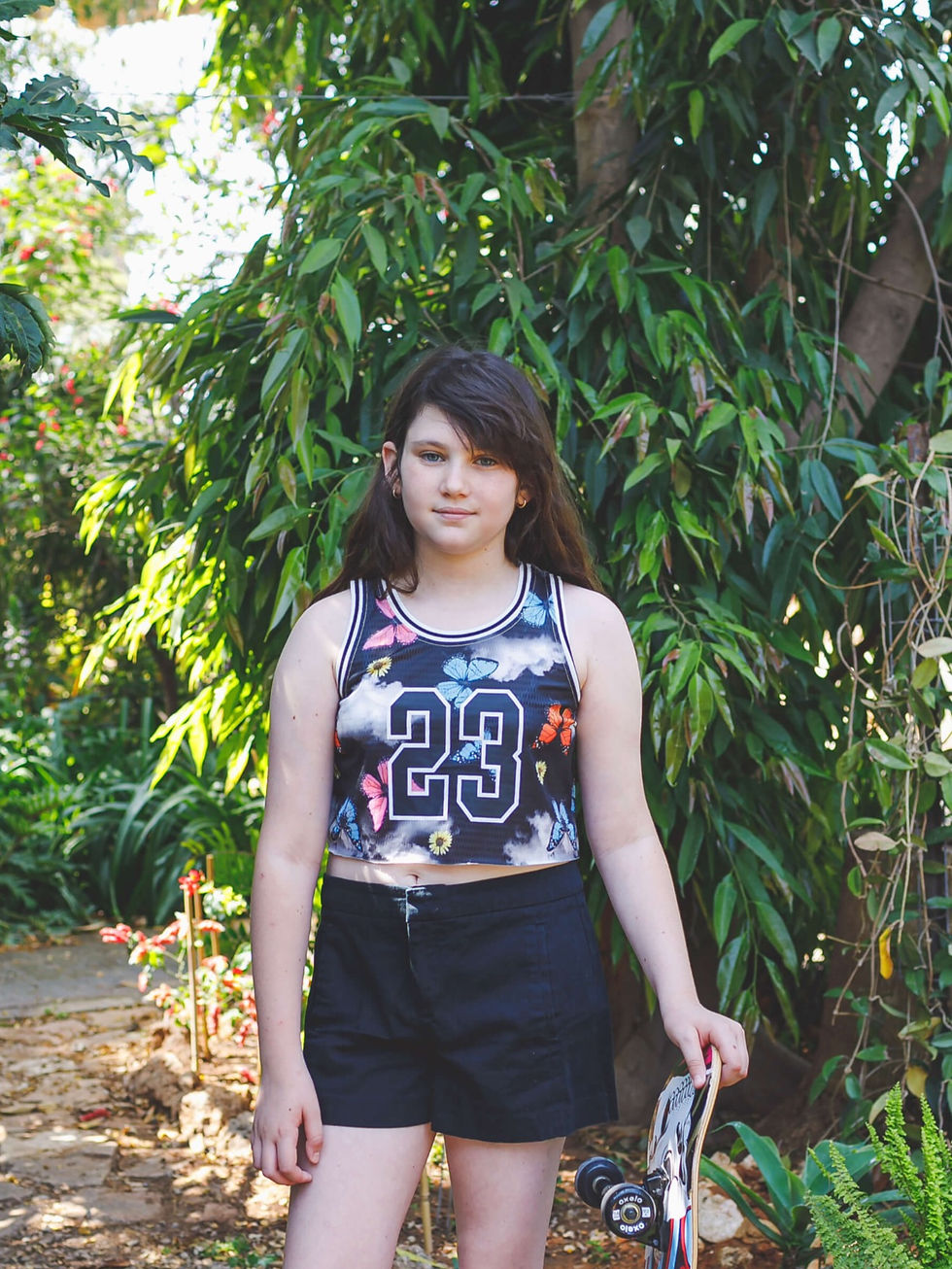נערה צעירה לבושה בחולצת טנק טופ עם הדפס פרפרים ומספר 23