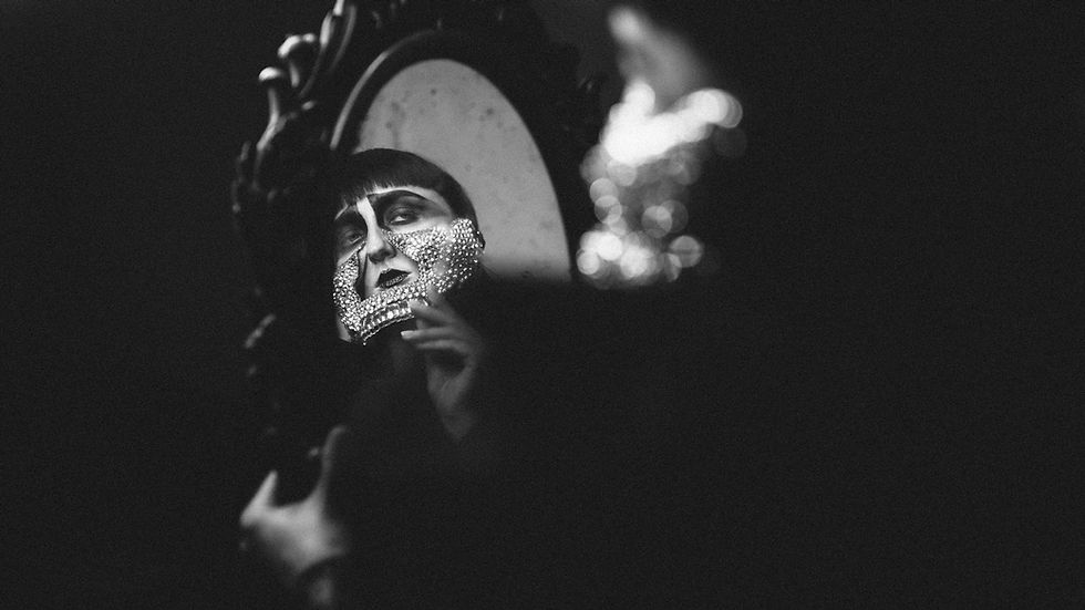 Captivating black and white portrait of a woman's reflection in an ornate mirror.