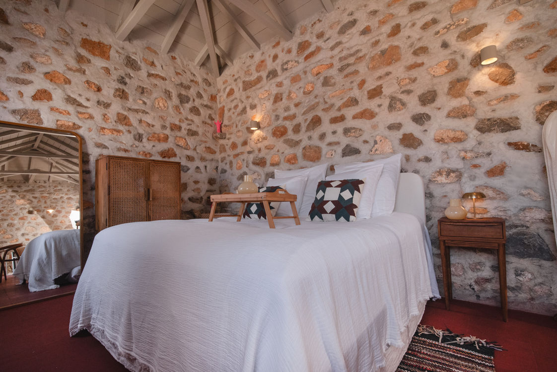 Schlafzimmer mit Steinwand und Doppelbett.