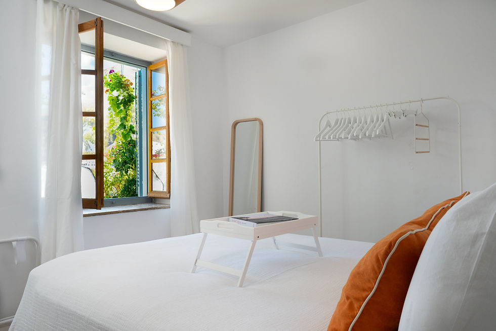 Helles Schlafzimmer mit offenem Fenster und Blumenblick in der Villa auf Hydra