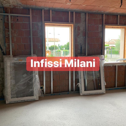 Interior view with windows and the text Infissi Milani, construction in progress.