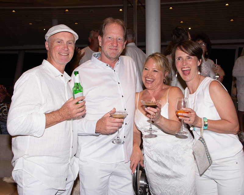 Two women and two men celebrating with cocktails at a white party on a Mediterranean event, representing lifestyle freedom and career reinvention after 40.