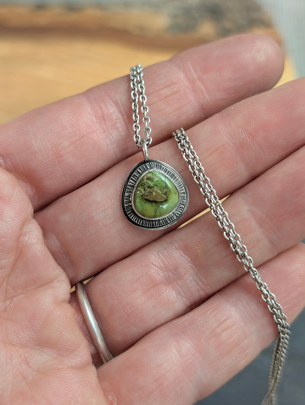 A handmade oxidised sterling silver pendant necklace featuring a green Sonoran Mountain Turquoise stone with sunburst design