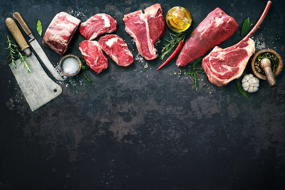Variety of raw beef meat steaks for grilling with seasoning and utensils on dark rustic bo