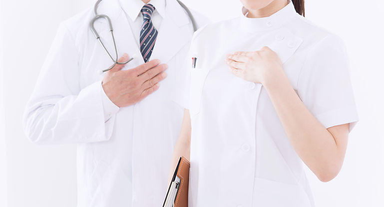 胸に手を当てた医師とスタッフ