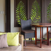 Villa verandah with dining table and daybed with green cushioned chairs
