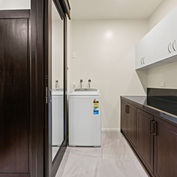 Butlers pantry with washing machine and dark cabinetry