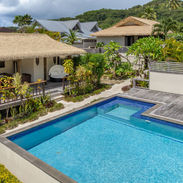 Aerial view of the pool deck with villa rooftops and mountains in the background.