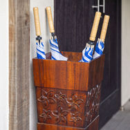 Guest umbrellas in a carved wooden holder stored at the entrance hut