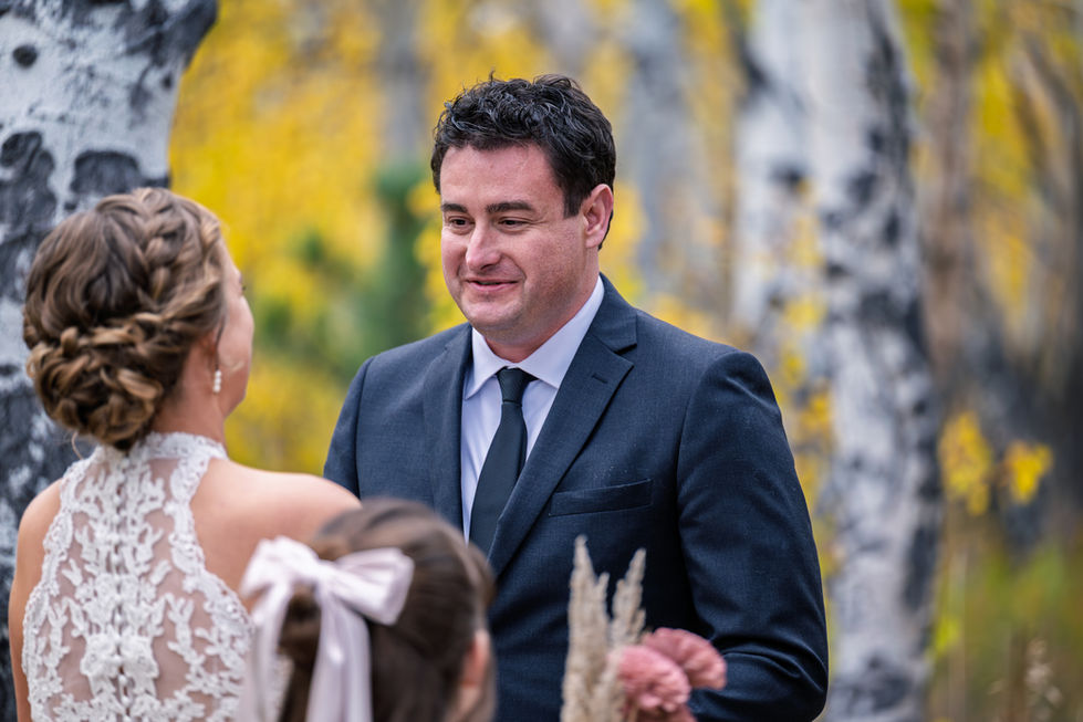 Man in suit at outdoor wedding ceremony.