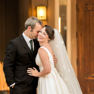 the bride and groom are posing for a picture and the groom is kissing the bride on the cheek