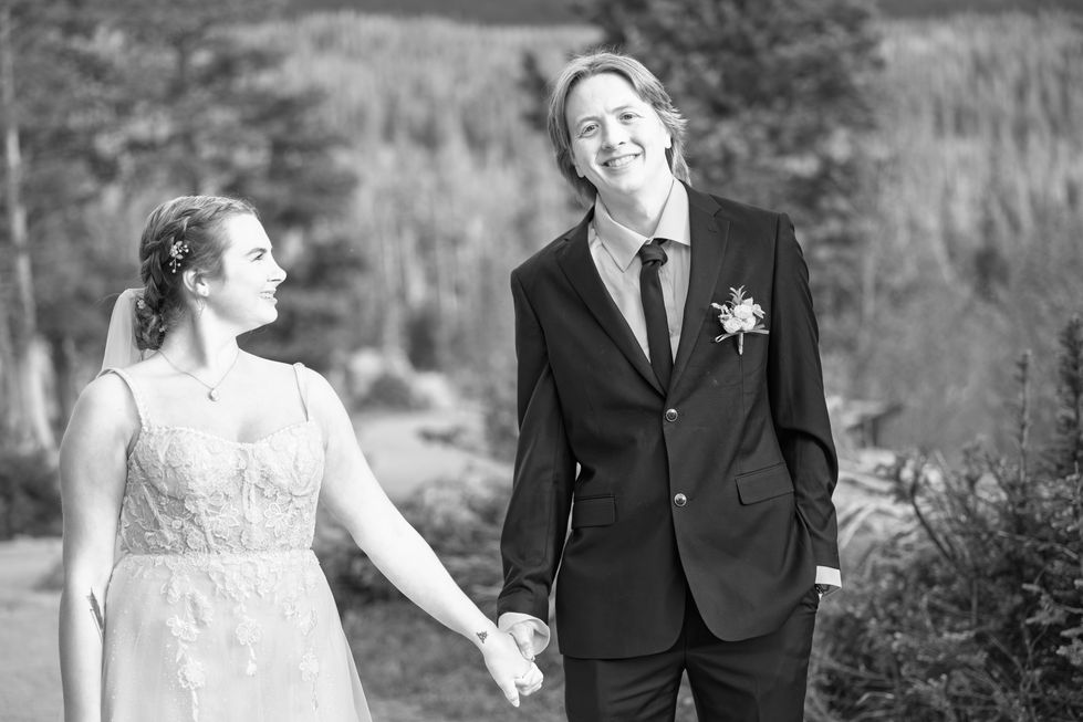 a black and white photo of a bride and groom holding hands