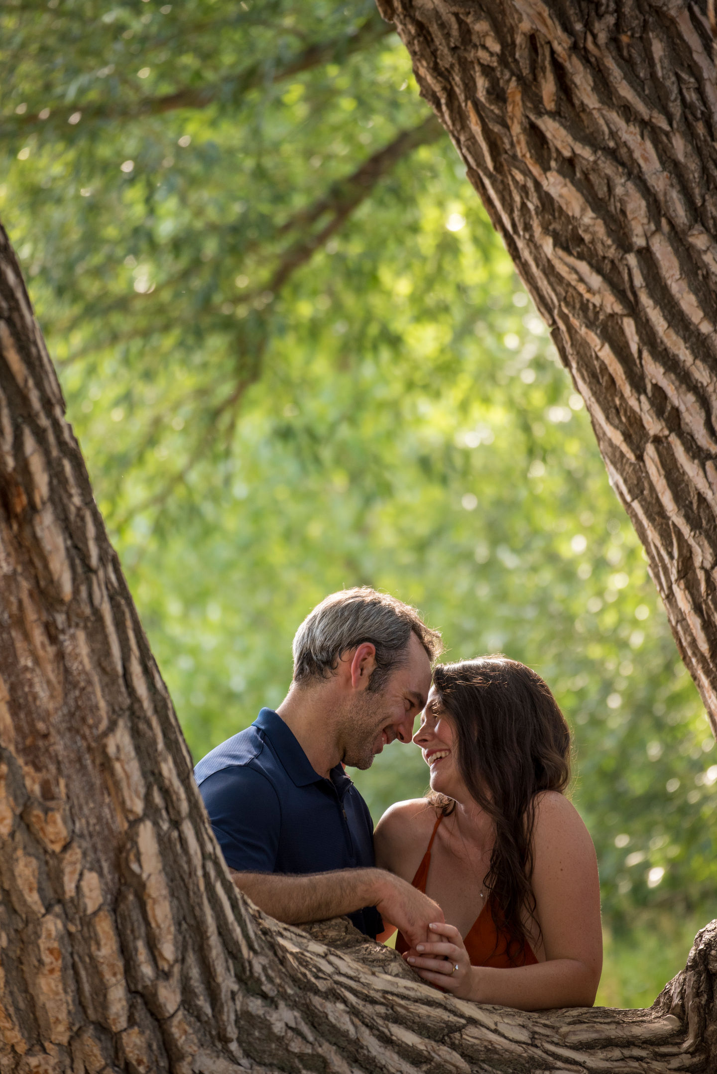 a man and a woman looking at each other between two trees