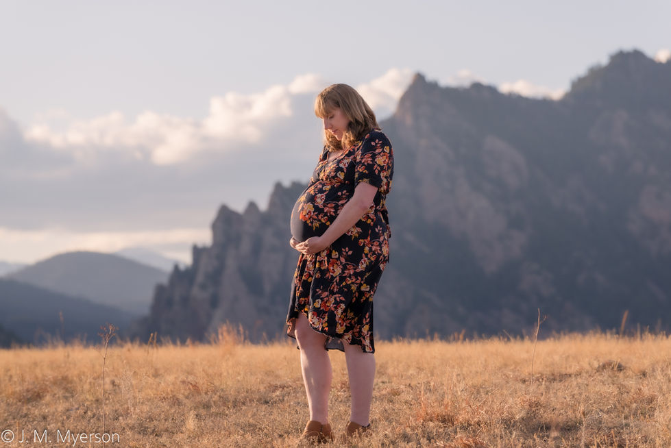 a pregnant woman in a field with mountains in the background