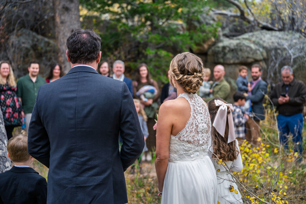 Bride and groom facing guests in outdoor setting.
