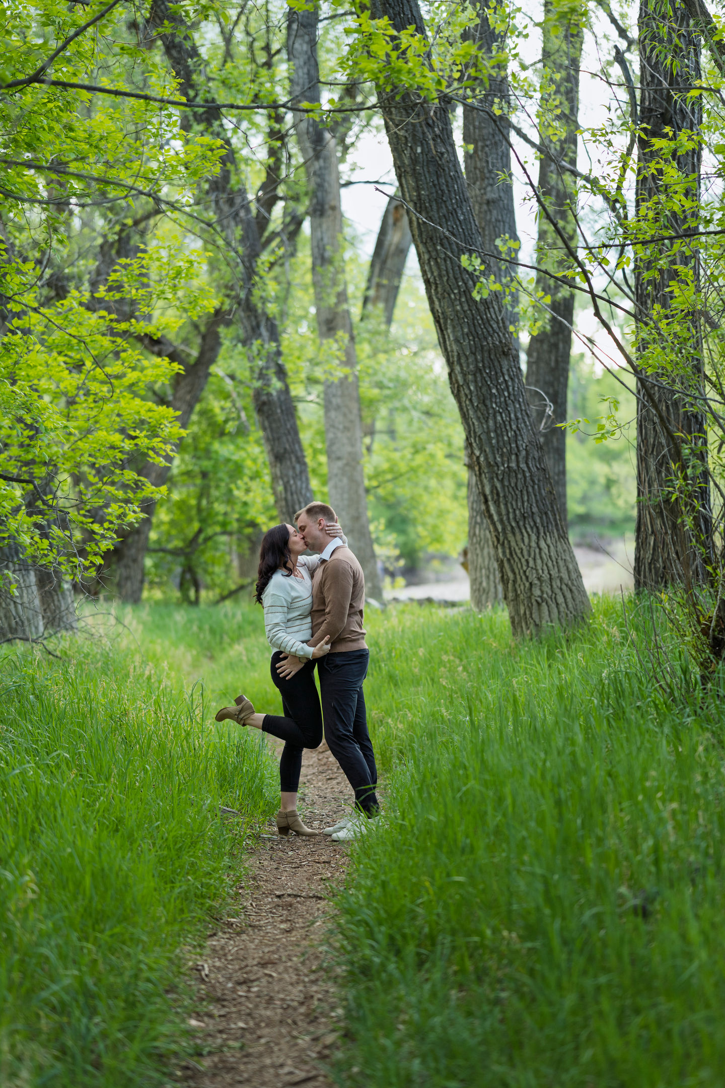 a man and woman are kissing on a path in the woods
