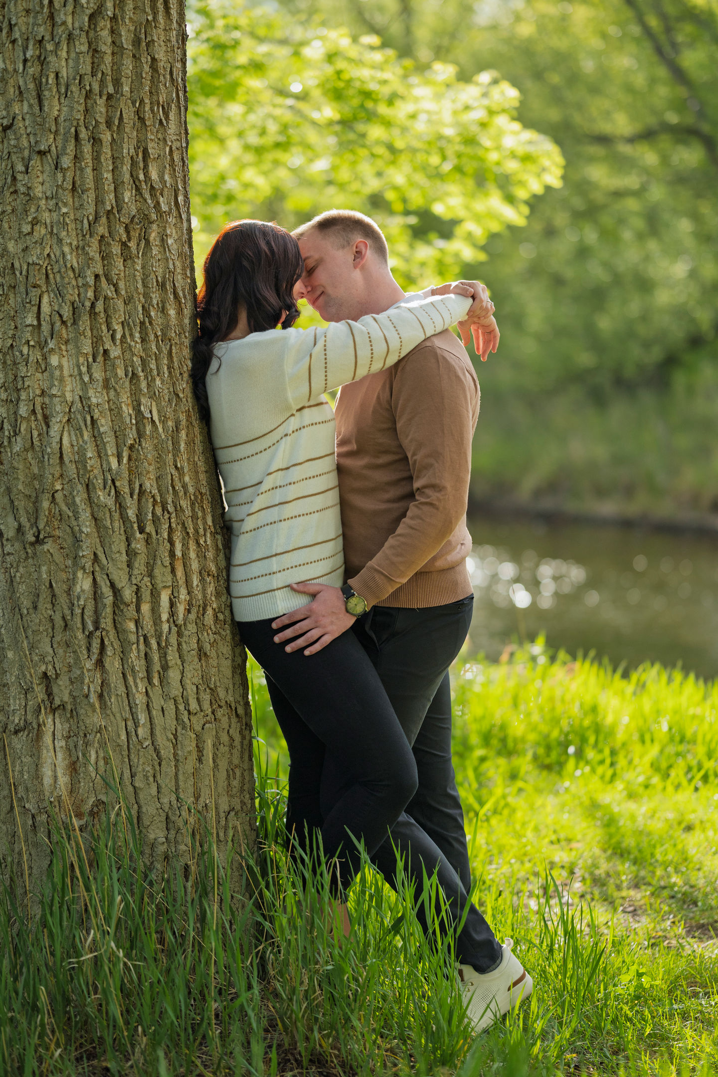a man and a woman leaning against a tree
