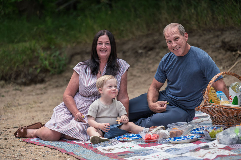 Family enjoying a picnic on a blanket outdoors.