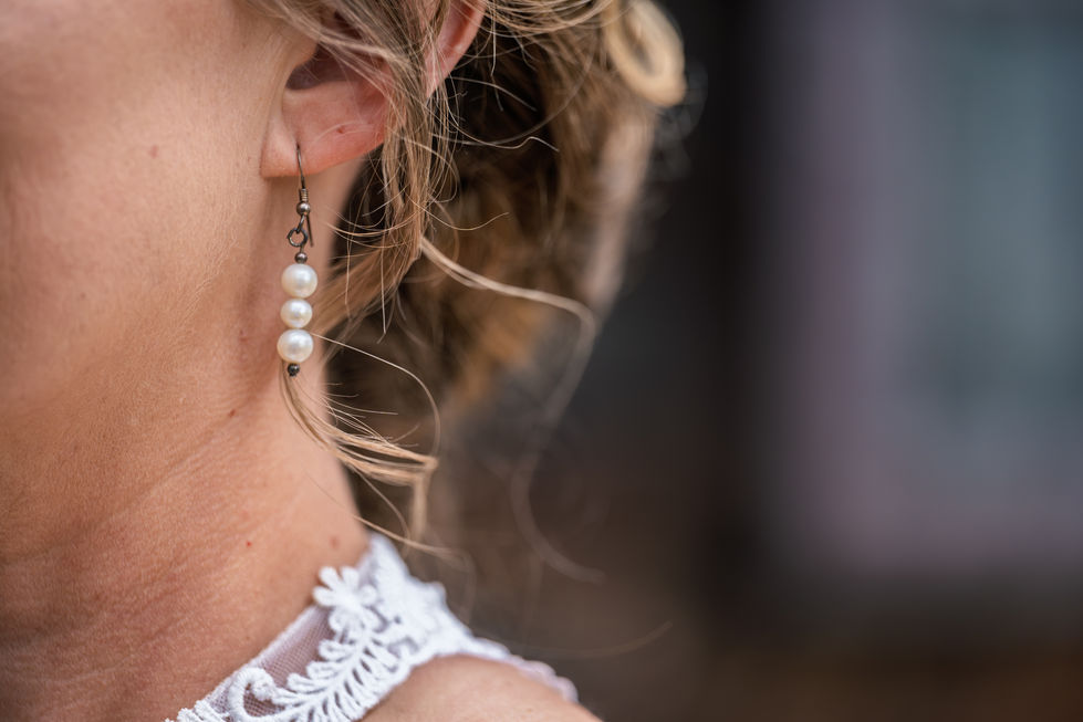 Close-up of earrings and lace detail on person.