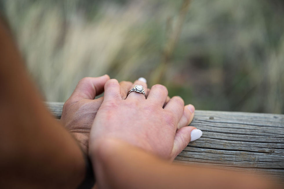 Close-up of an engagement ring on a woman's hand resting on a wooden bridge railing at Eldorado Canyon State Park Colorado