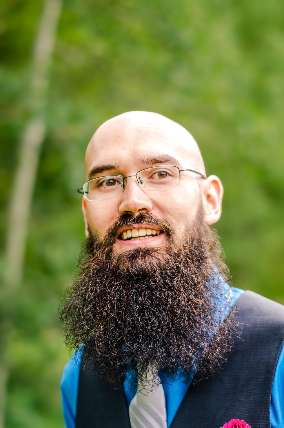 a bald man with glasses and a beard smiles for the camera