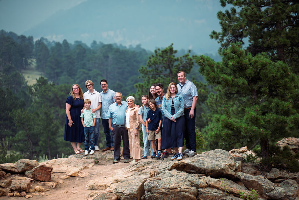 Family posing on rocky terrain with forest background.