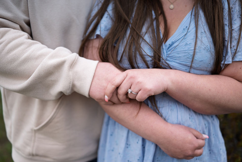 a woman wearing an engagement ring is holding a man 's hand