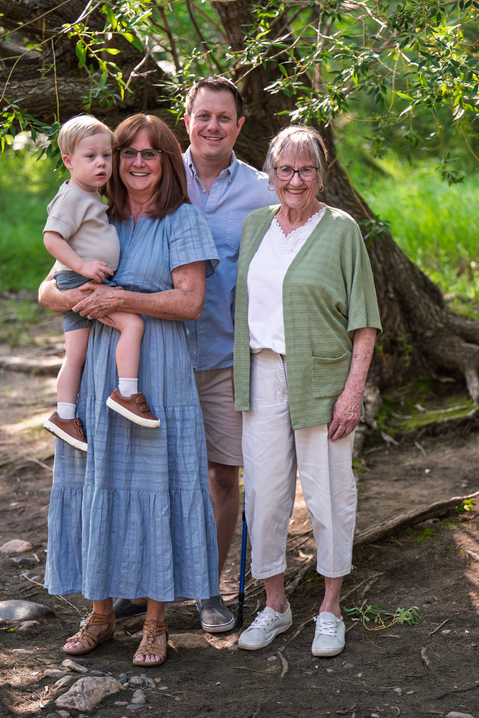 Four people posing outdoors, including a child.