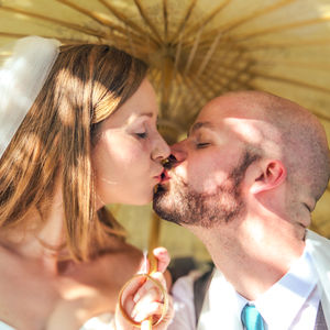 a bride and groom are kissing under an umbrella