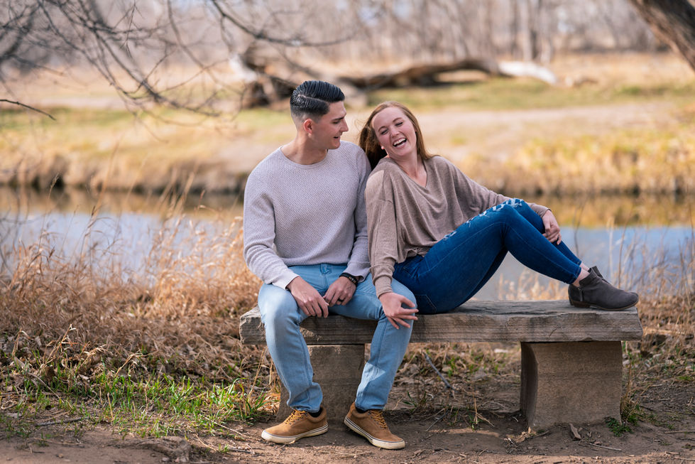 a man and a woman sit on a bench laughing