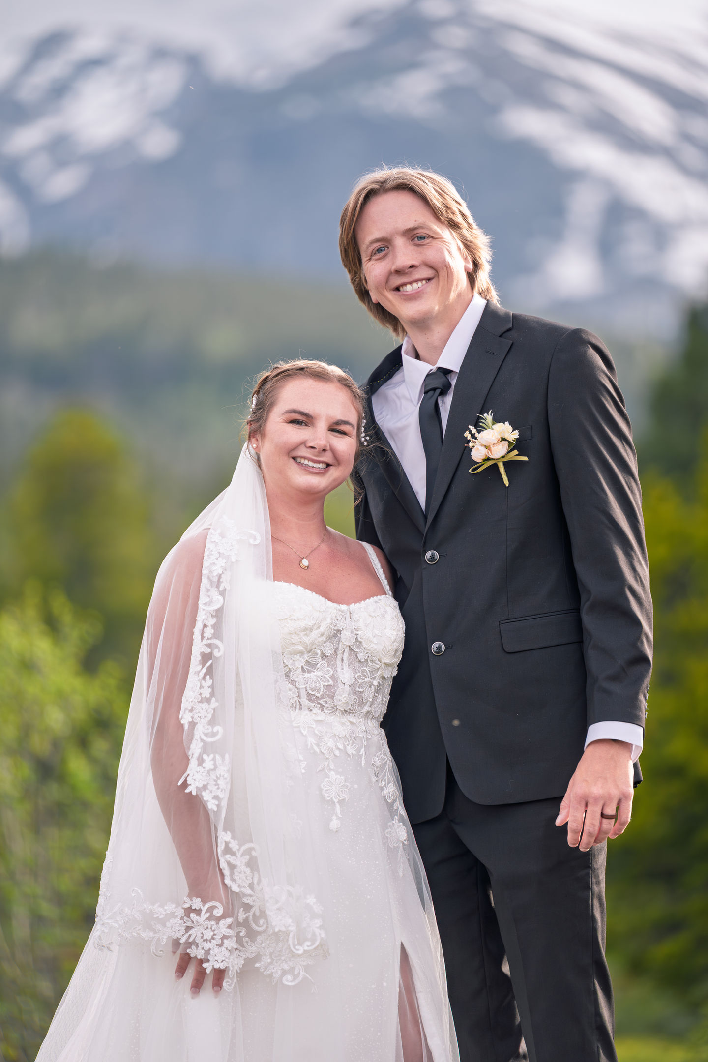 a bride and groom posing for a picture with mountains in the background