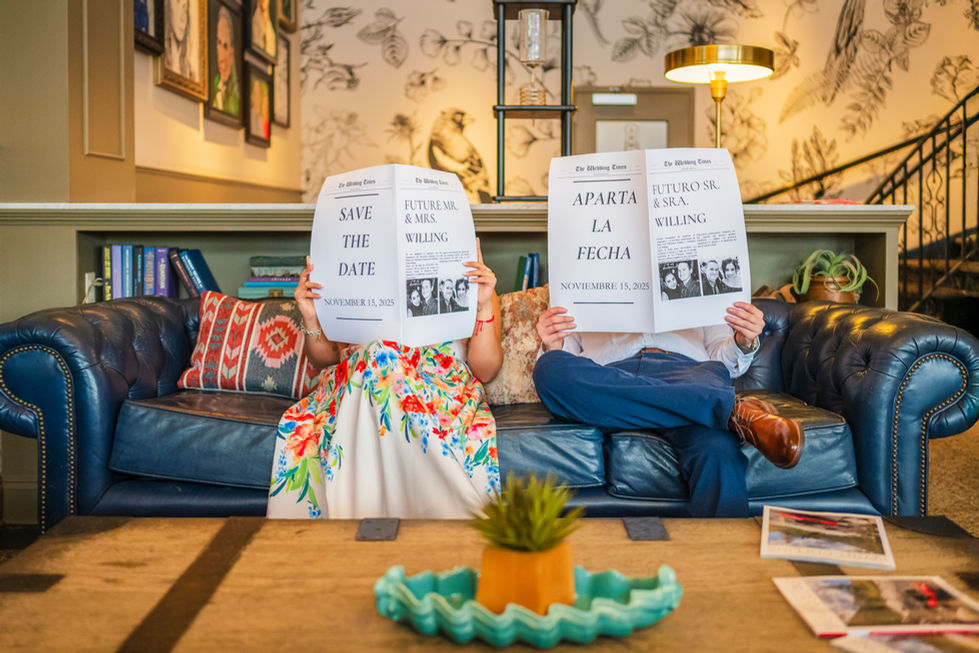 a man and woman sitting on a couch holding newspapers that say save the date