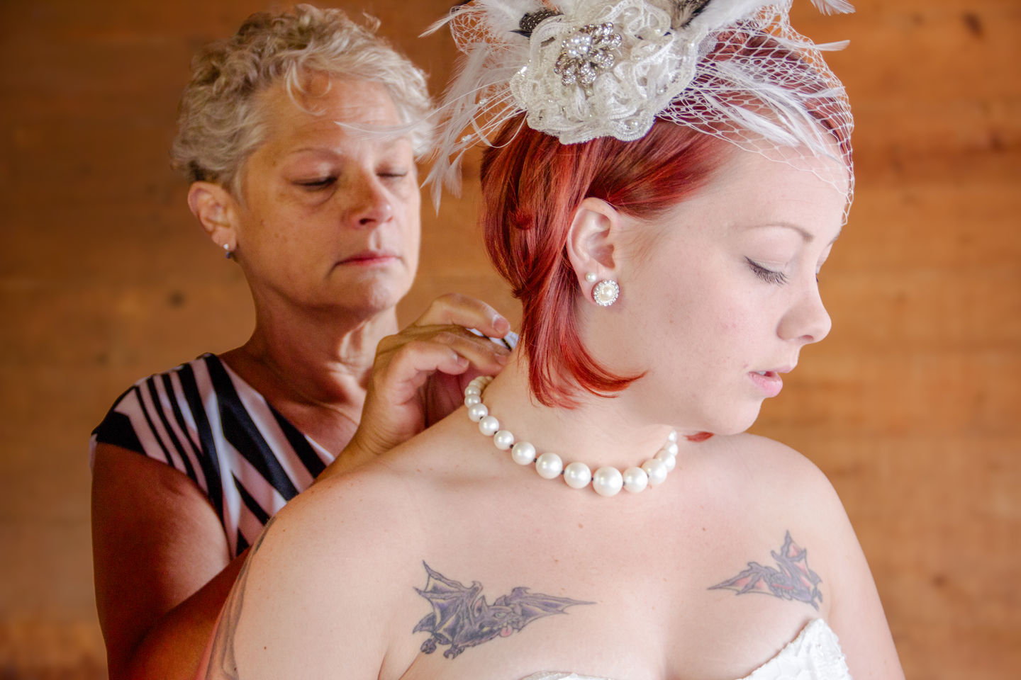 a woman helps a woman with her pearl necklace