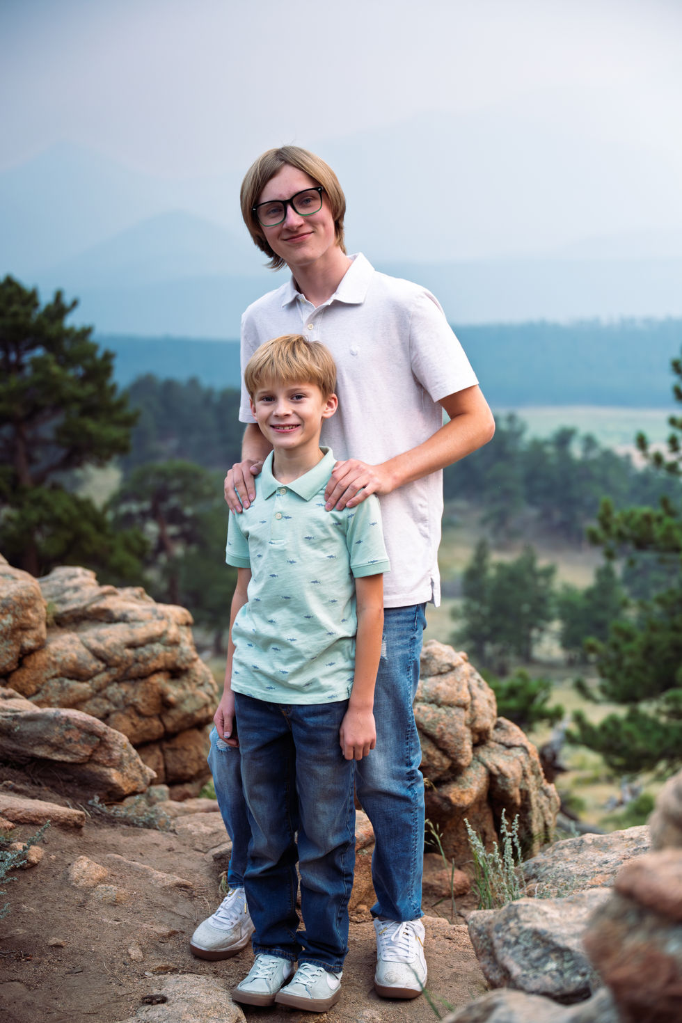Two people smiling outdoors in a natural setting.