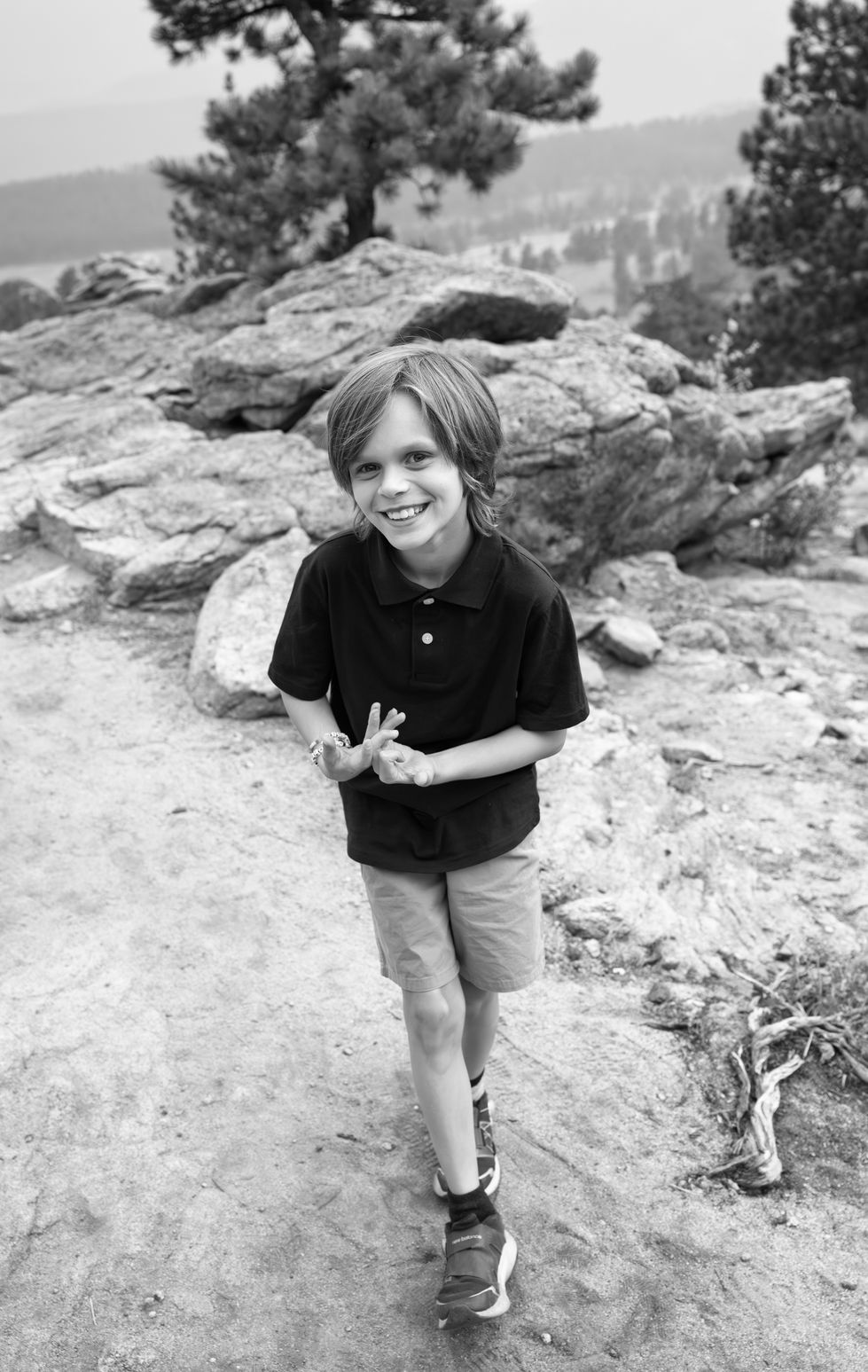 Young child smiling outdoors in black and white.
