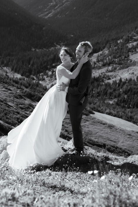 a black and white photo of a bride and groom on top of a mountain