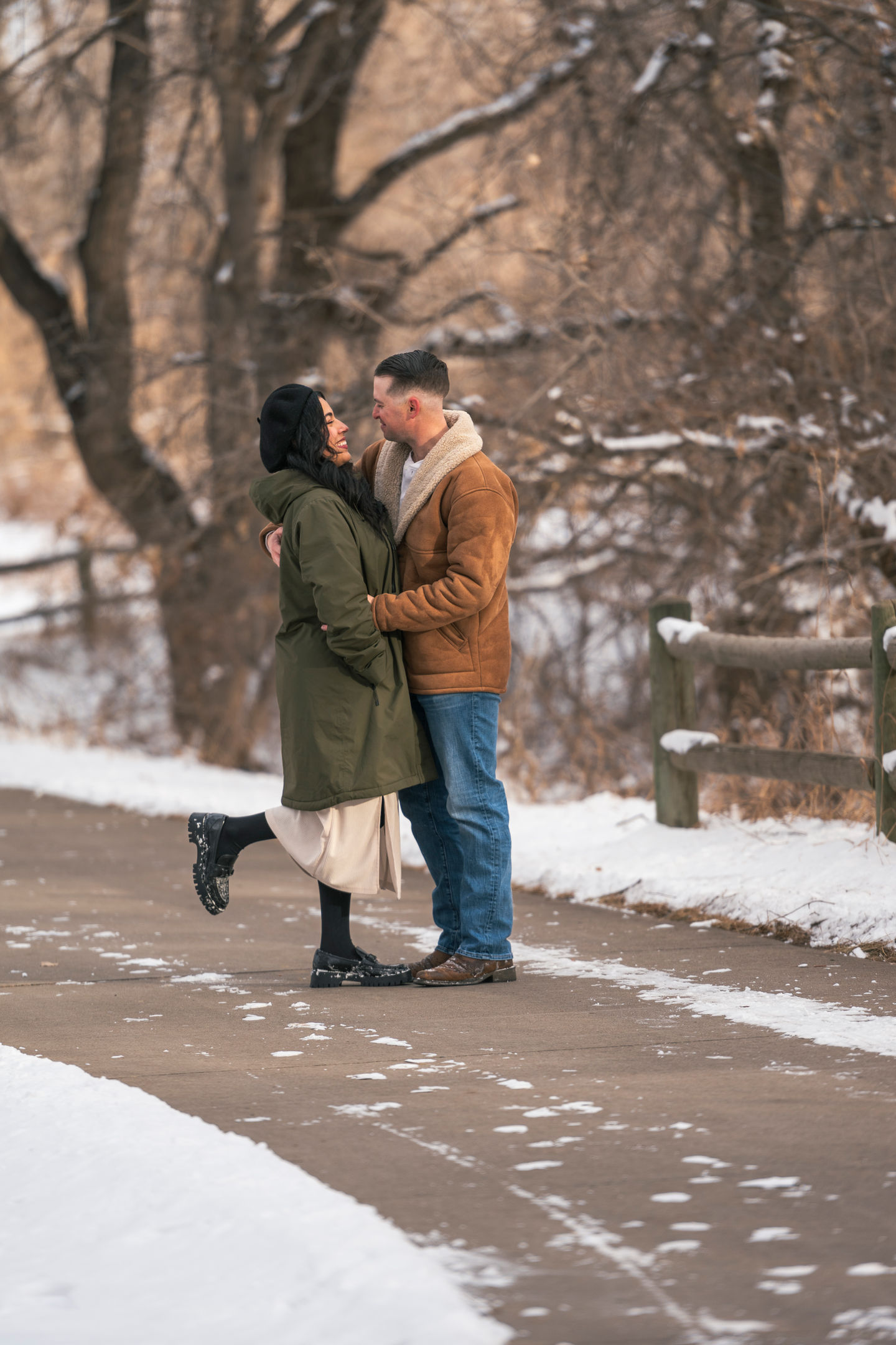 a man in a brown jacket holds a woman in a green coat