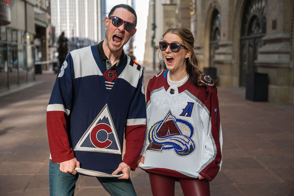 Two people wearing hockey jerseys, excited expressions.