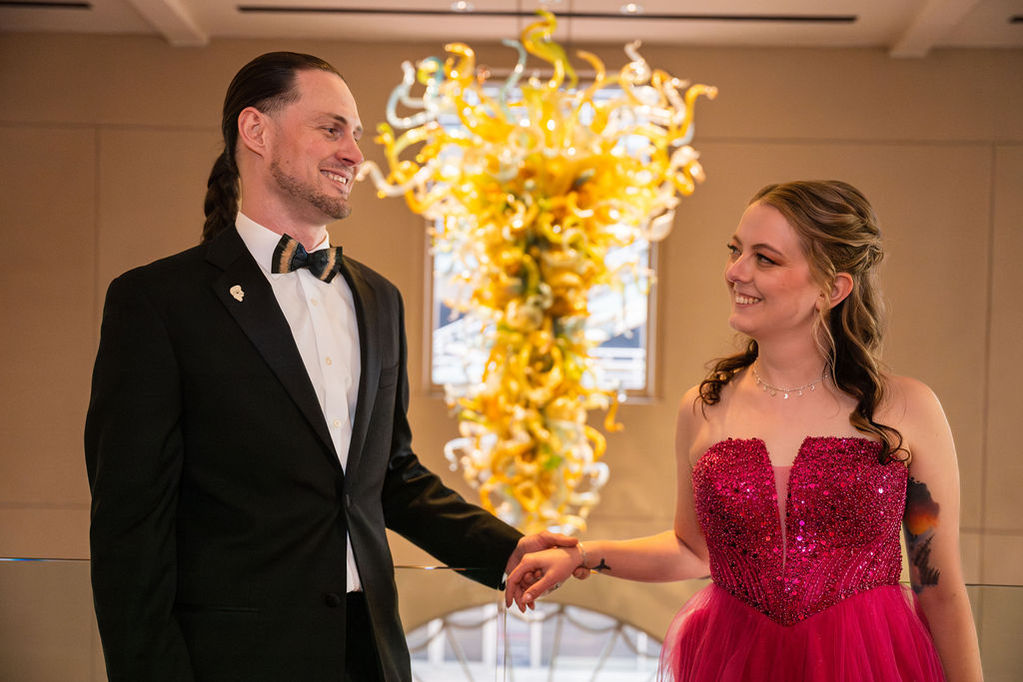 Couple holding hands, smiling, with artistic background.